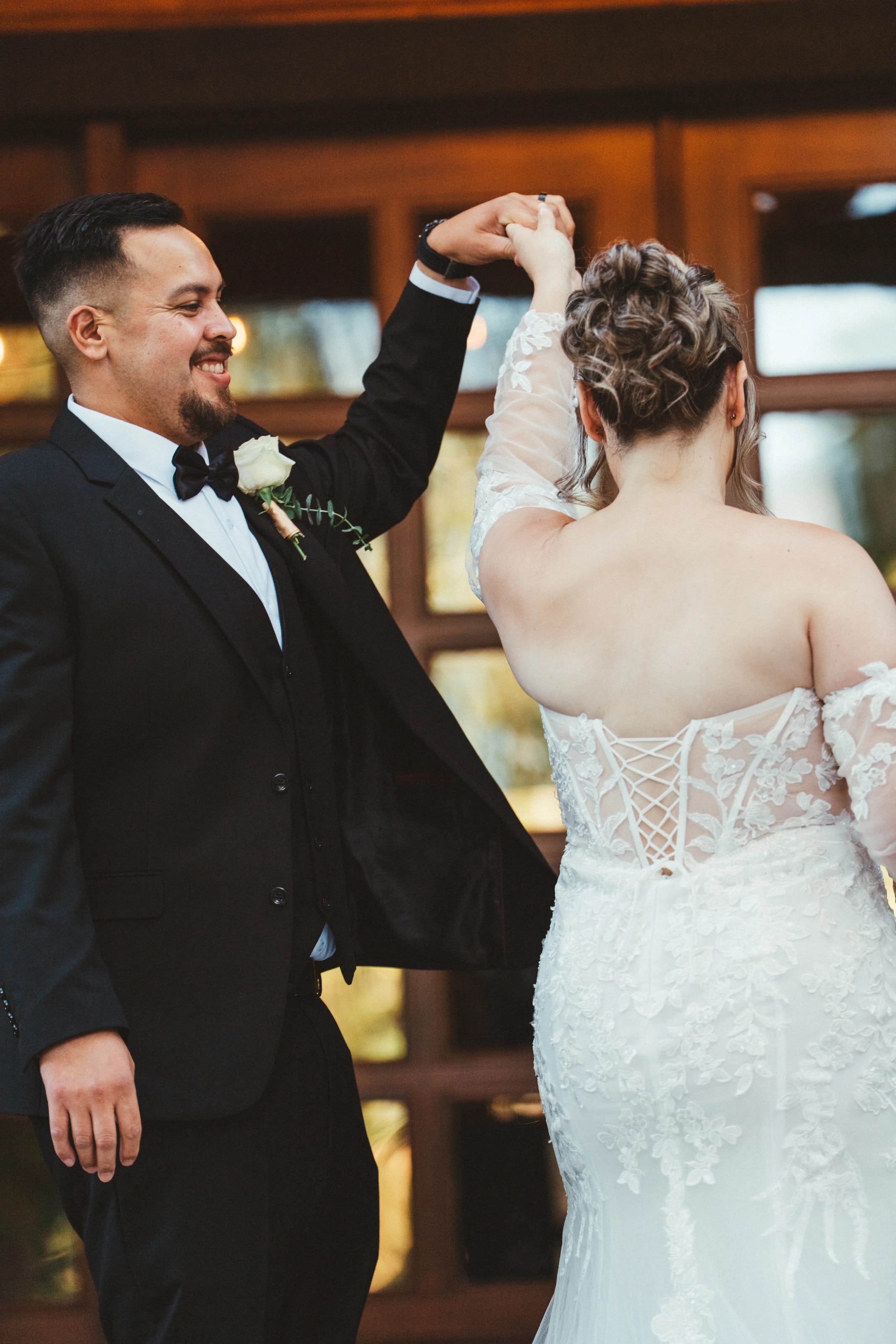 El novio hace girar a la novia en su primer baile, los dos sonriendo