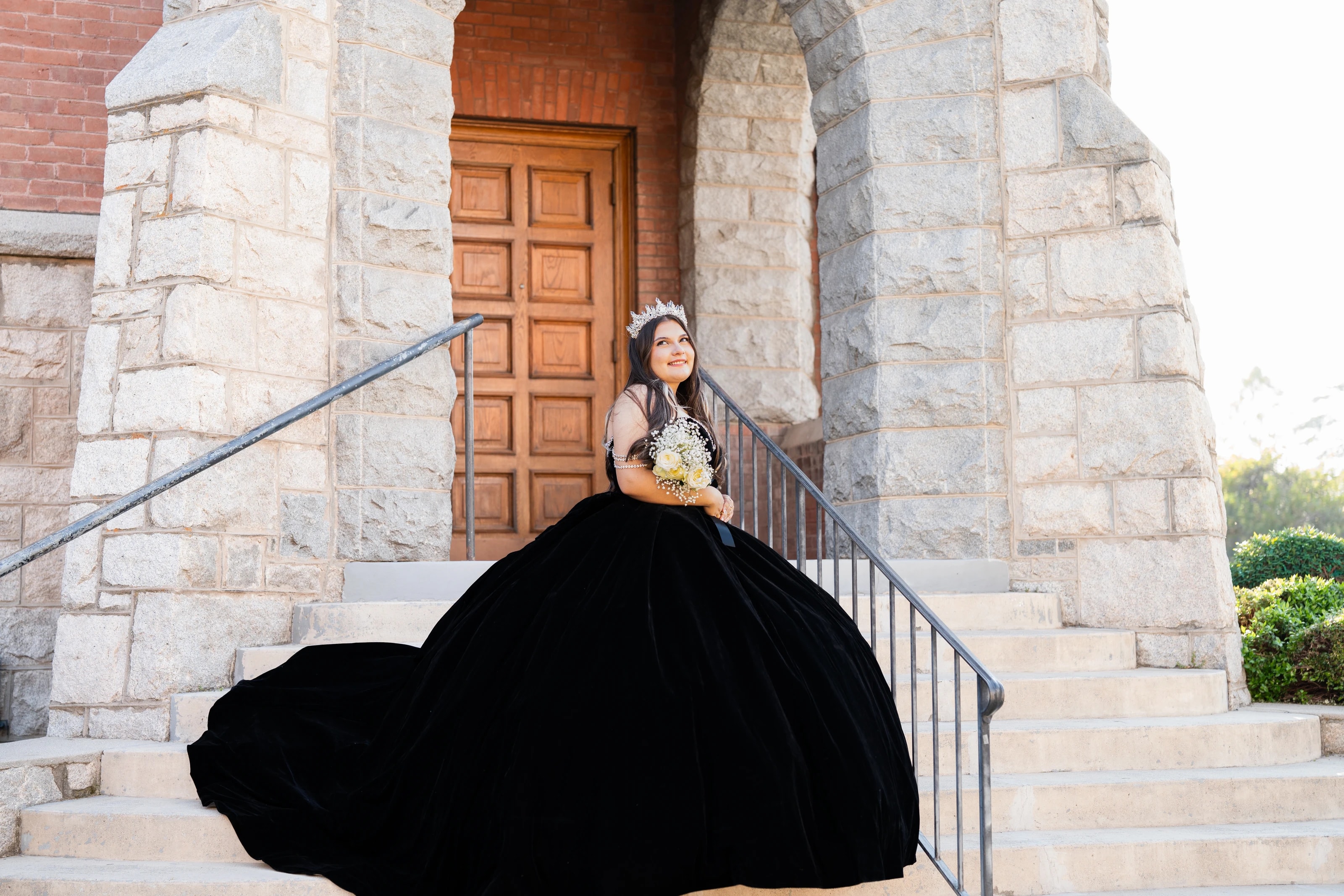 Su vestido de terciopelo se extiende por las escaleras de la iglesia mientras mira hacia arriba