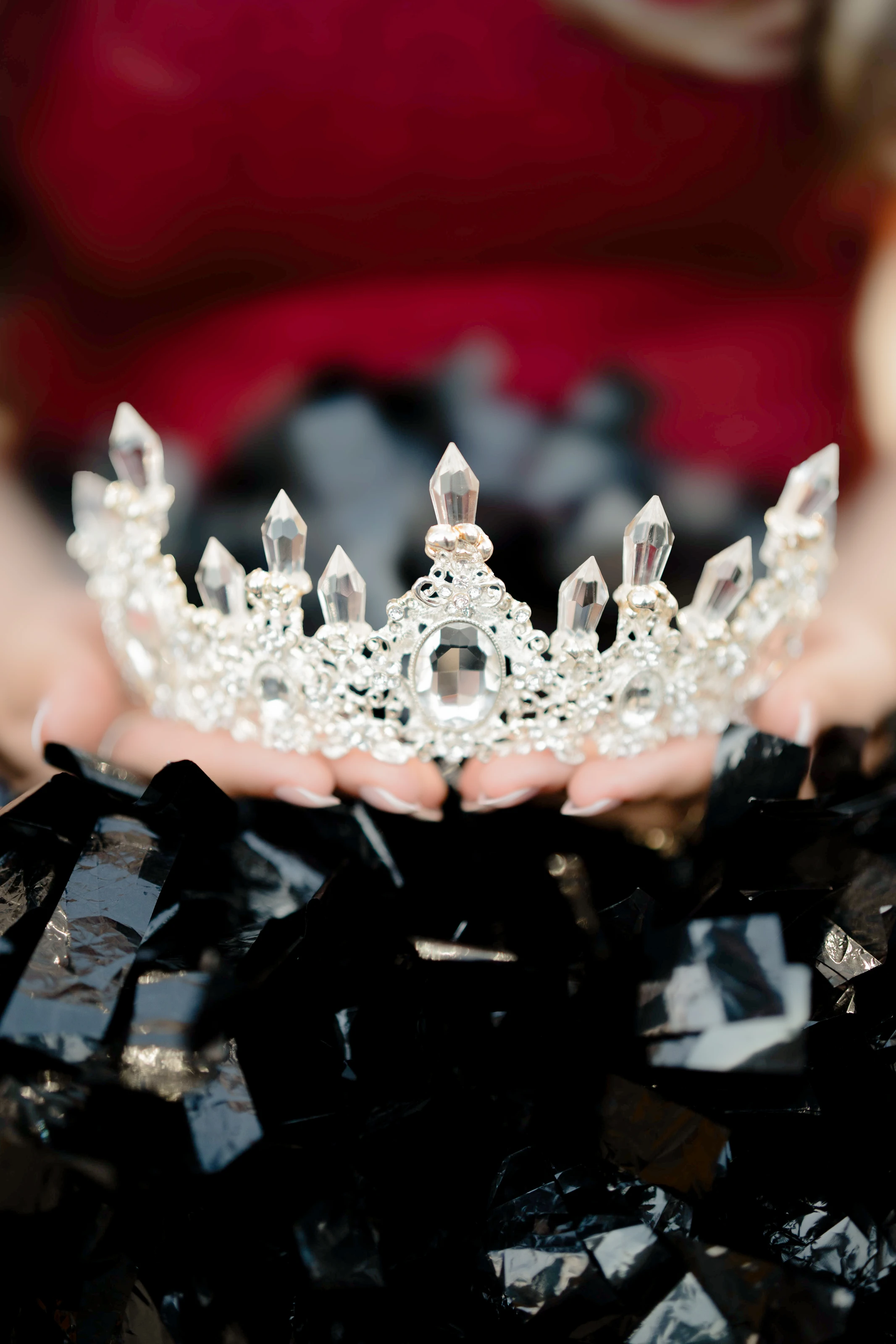 Her hands hold a crystal crown over her black gown