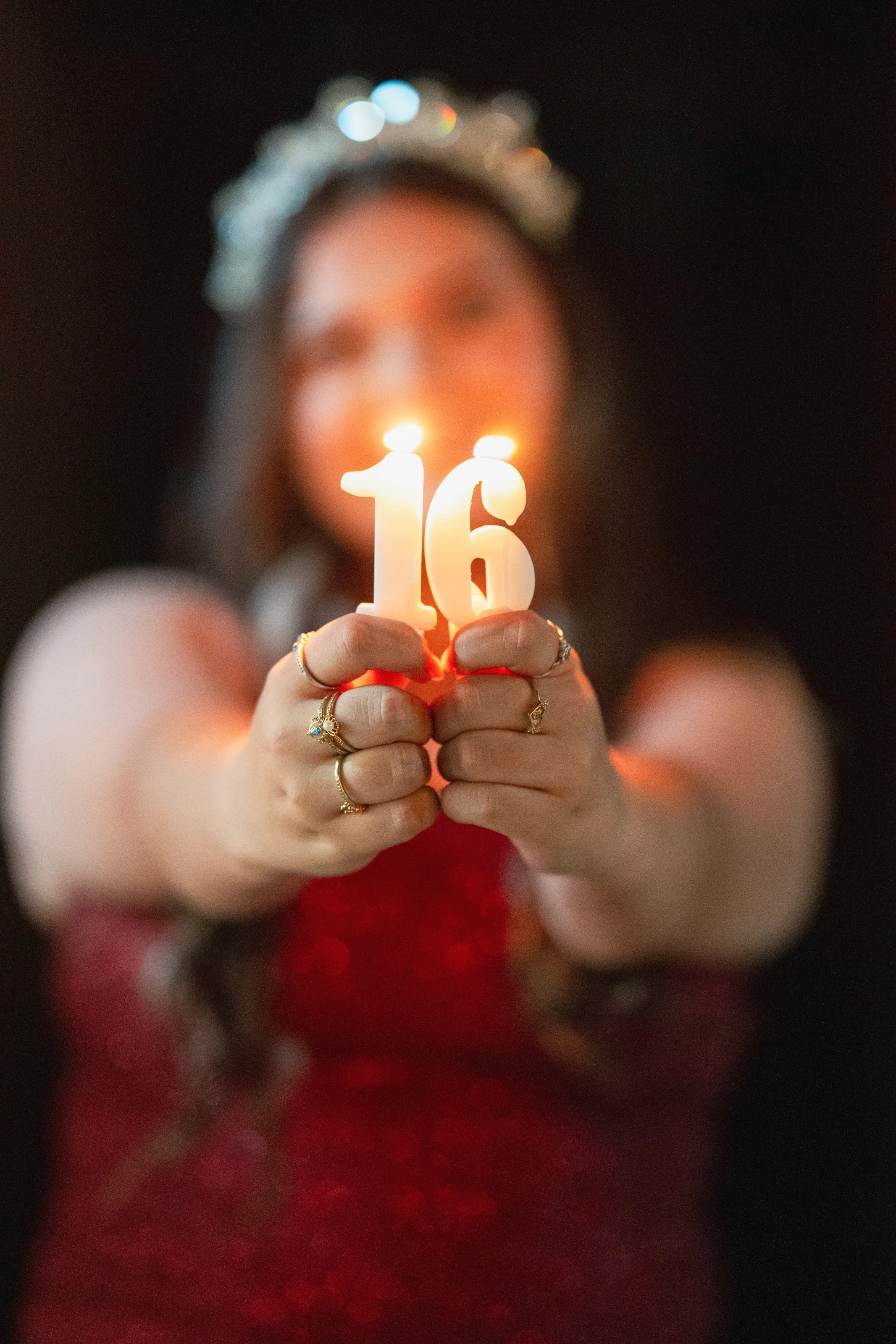 Sostiene hacia la cámara una vela encendida con el número 16